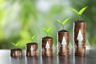 Image of Investment. Stacked coins with seedlings on tops and arrows against blurred background