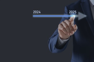 New year goals. Businessman touching arrow with 2024 and 2025 on virtual screen against black background, closeup