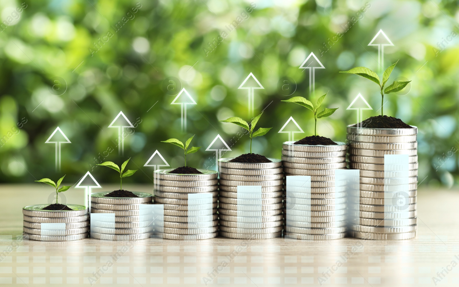 Image of Investment. Stacked coins with seedlings on tops and arrows against blurred background