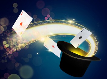 Image of Magician's hat with playing cards and magic light on dark blue background