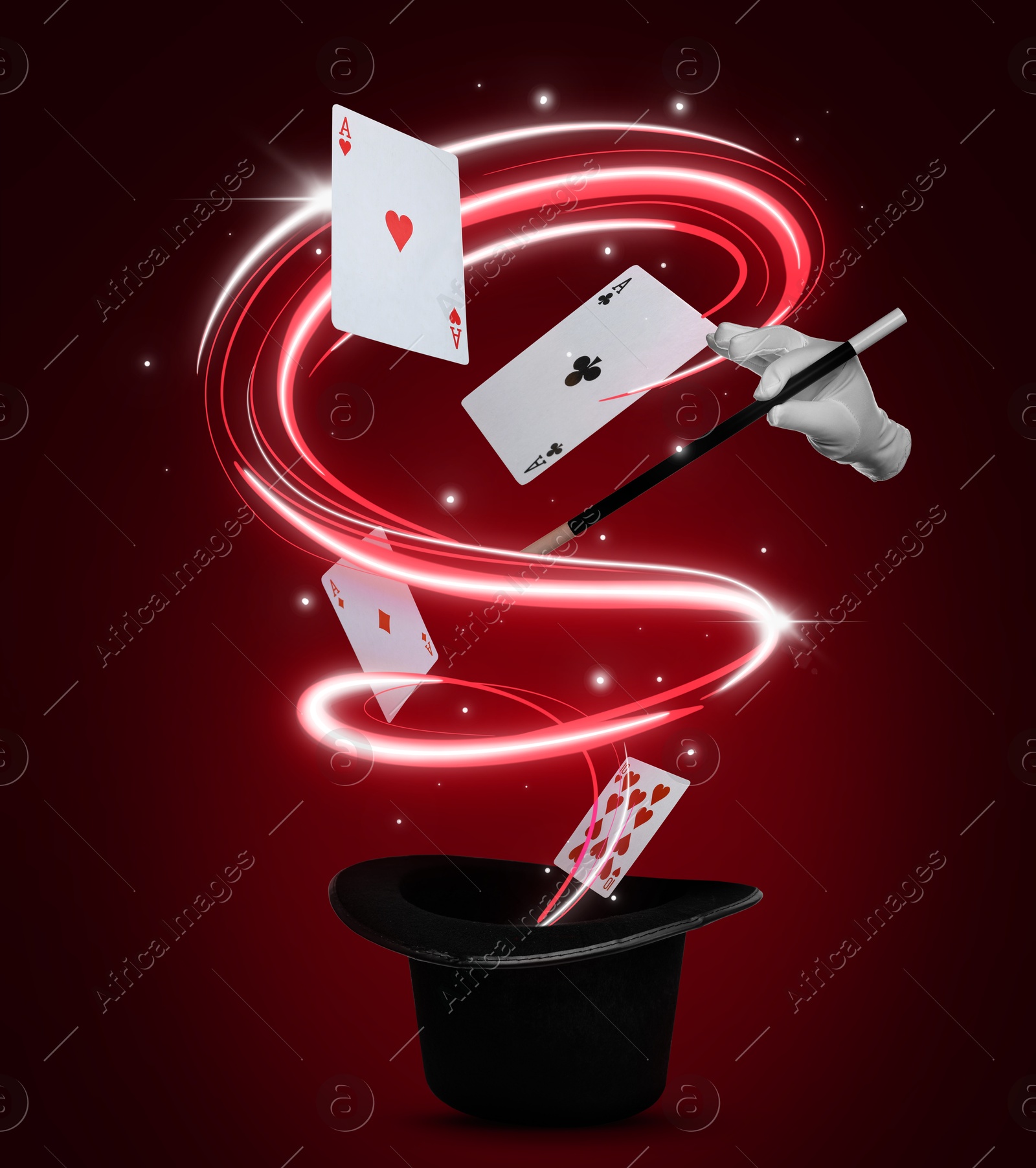 Image of Magician showing trick with magic wand on red background. Playing cards and light flying out of top hat