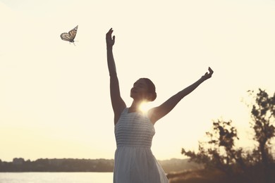 Woman and butterfly near river in morning. Beauty, health, spring, freedom