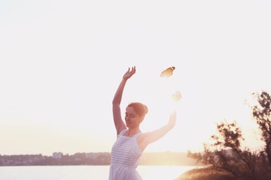 Butterfly flying over dancing woman near river in morning. Beauty, health, spring, freedom