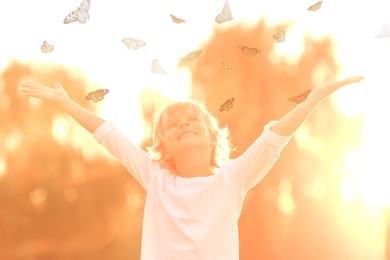 Image of Butterflies flying around happy child in nature at sunrise. Health, spring, freedom