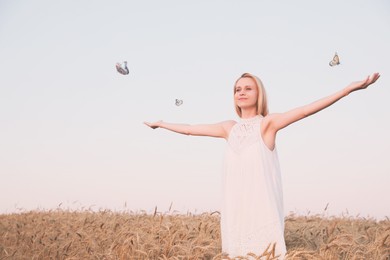 Image of Butterflies flying around happy woman in field at sunrise. Health, spring, freedom, beauty