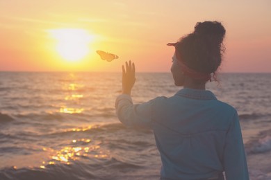 Woman and butterfly near sea at sunset. Health, spring, freedom, beauty