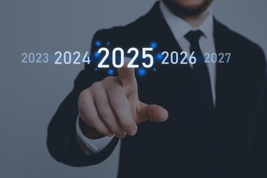 Image of New year goals. Businessman touching 2025 on virtual screen against grey background, closeup