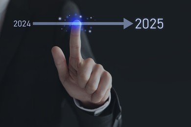 Image of New year goals. Businessman touching arrow leading from 2024 to 2025 on virtual screen against black background, closeup