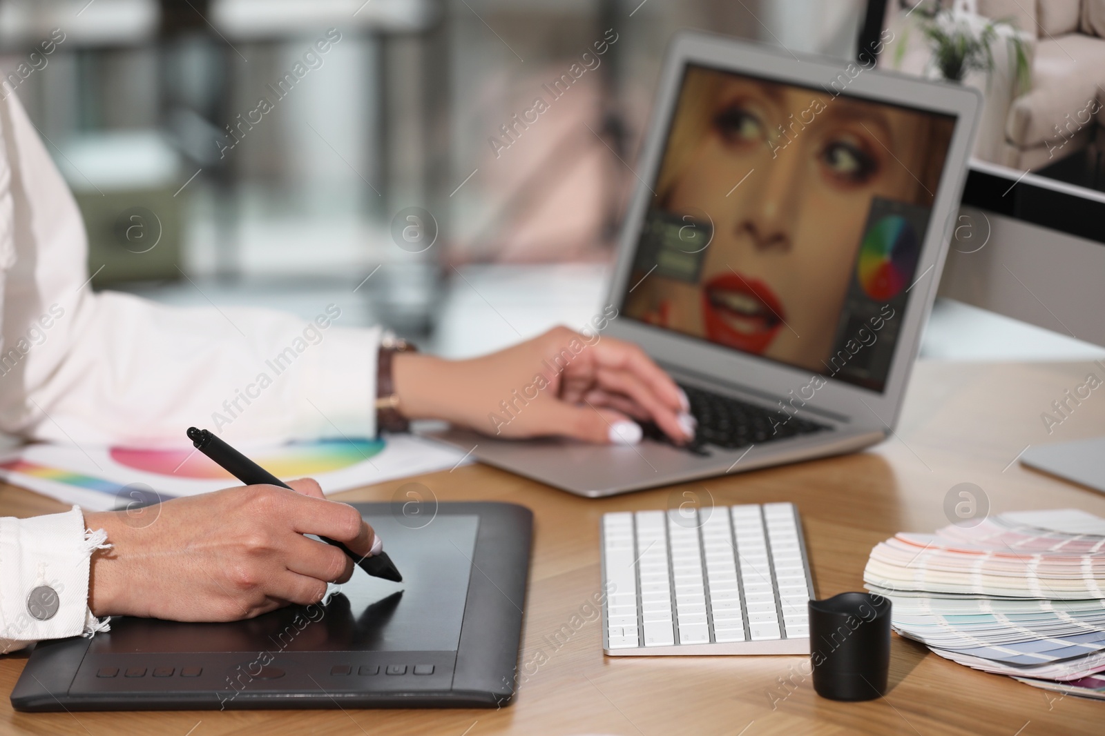 Photo of Professional retoucher working on graphic tablet and laptop at table, closeup