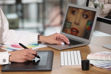 Photo of Professional retoucher working on graphic tablet and laptop at table, closeup