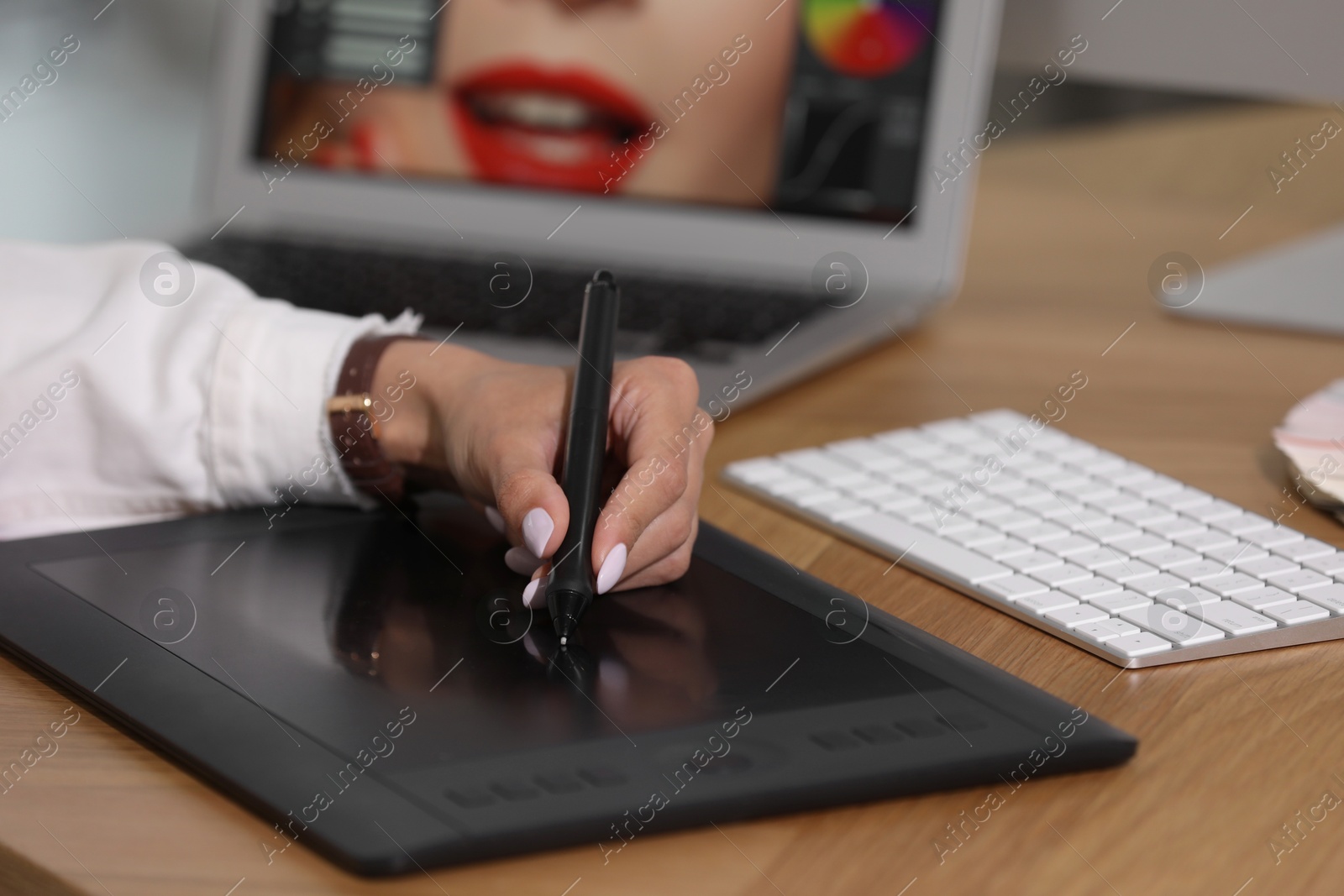 Photo of Professional retoucher working on graphic tablet at table, closeup