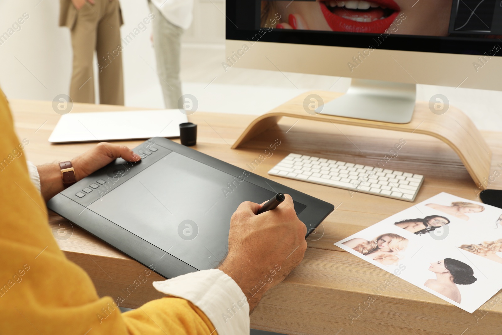 Photo of Professional retoucher working with graphic tablet at desk in photo studio, closeup