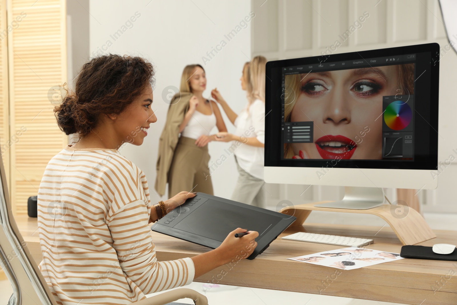 Photo of Professional African American retoucher working with graphic tablet at desk in photo studio