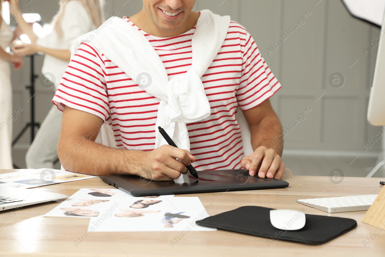 Photo of Professional retoucher working with graphic tablet at desk in photo studio, closeup