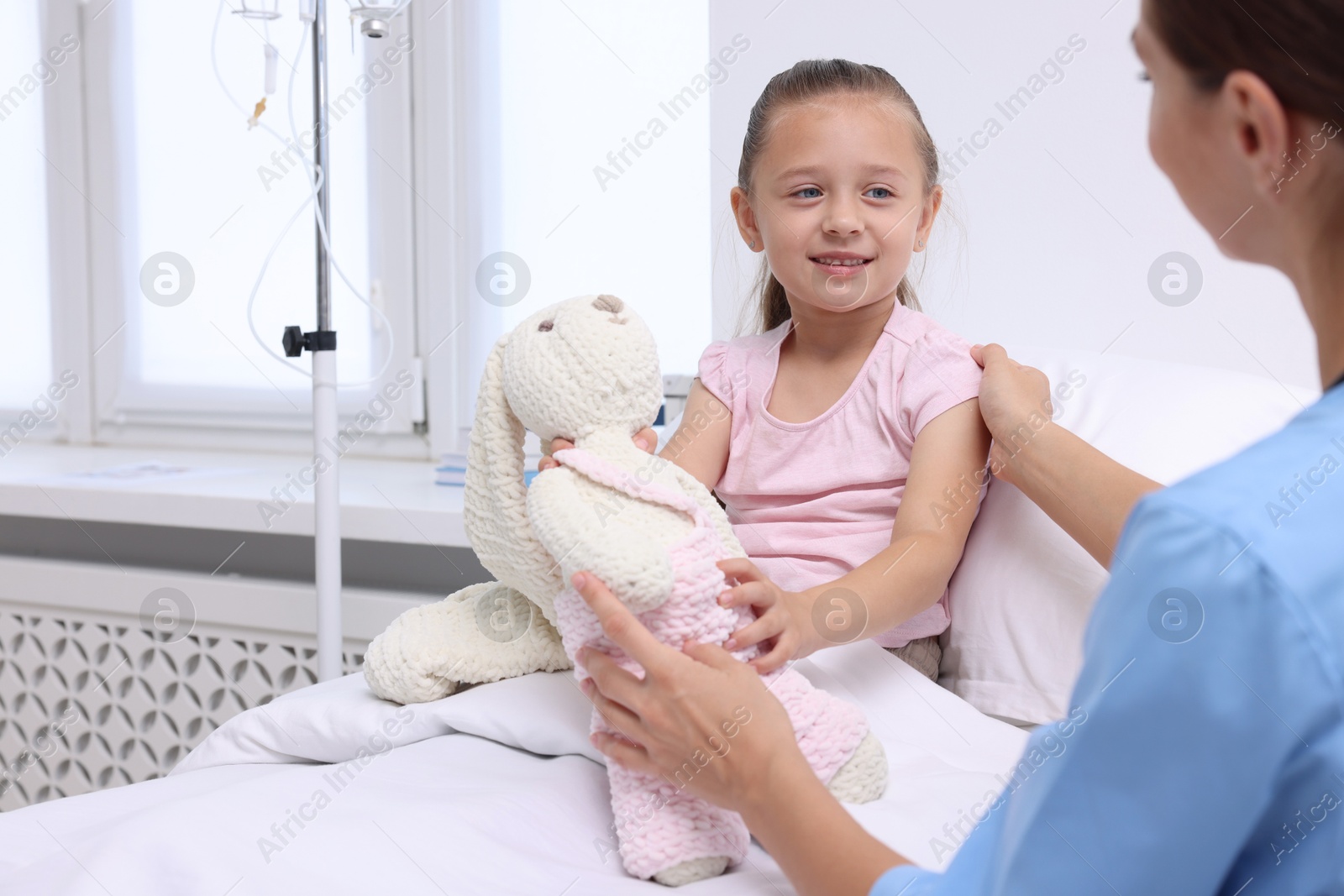 Photo of Doctor examining little girl on bed at hospital