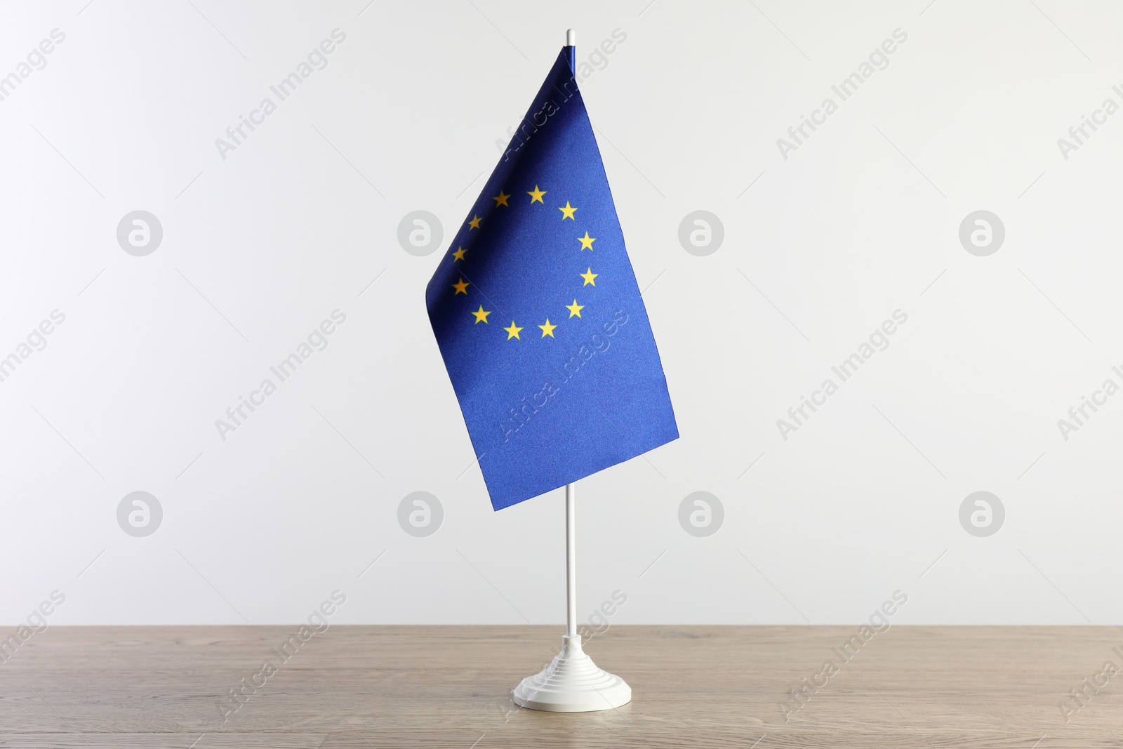 Photo of One flag of European Union on wooden table against white background