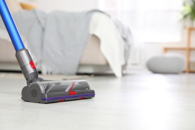 Photo of Cleaning floor with cordless vacuum cleaner indoors, closeup. Space for text