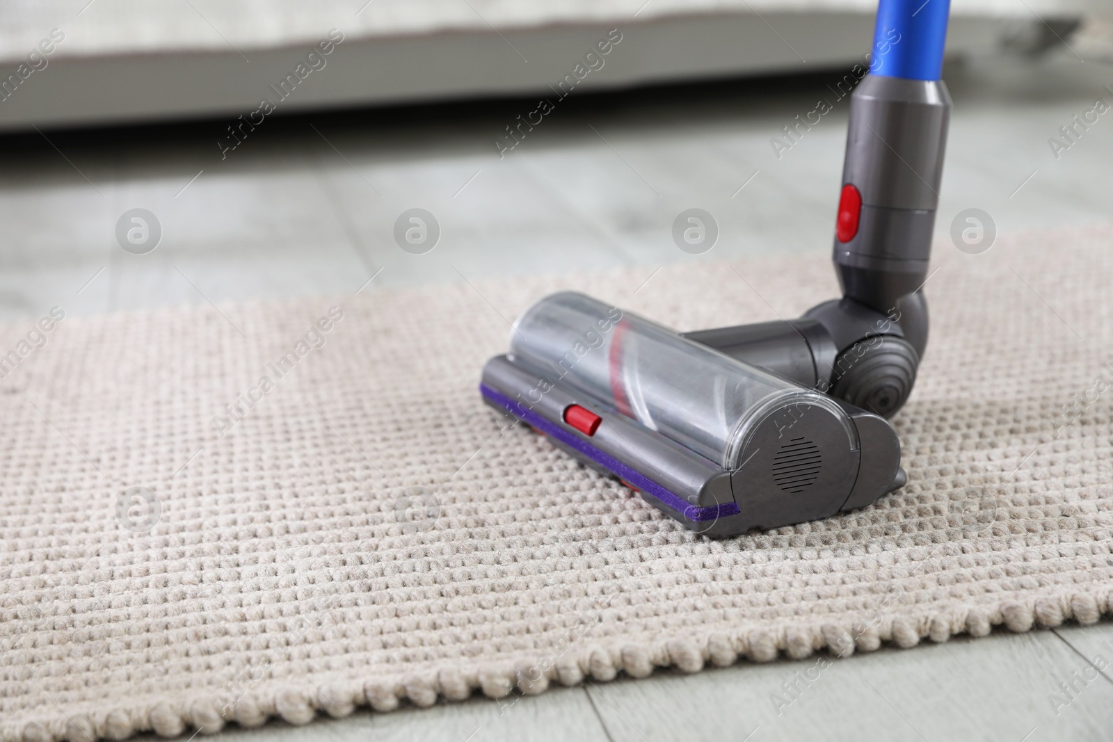 Photo of Cleaning carpet with cordless vacuum cleaner indoors, closeup. Space for text