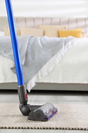 Photo of Cleaning carpet with cordless vacuum cleaner indoors, closeup. Space for text