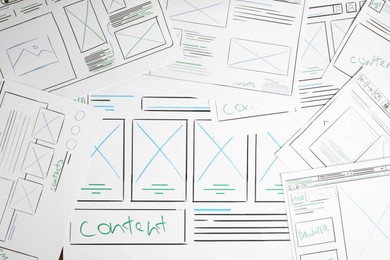 Photo of Developing UI design. Sketches of website wireframes on as background, top view