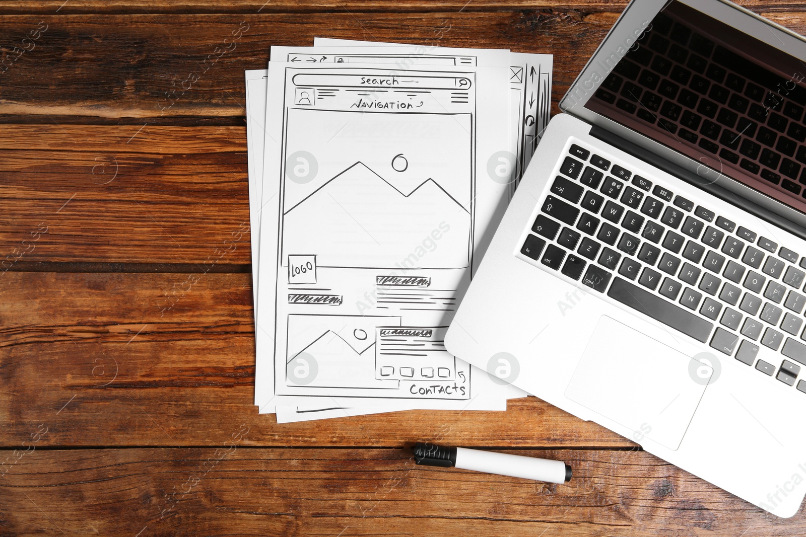 Photo of Developing UI design. Sketches of website wireframes, laptop and felt pen on wooden table, top view