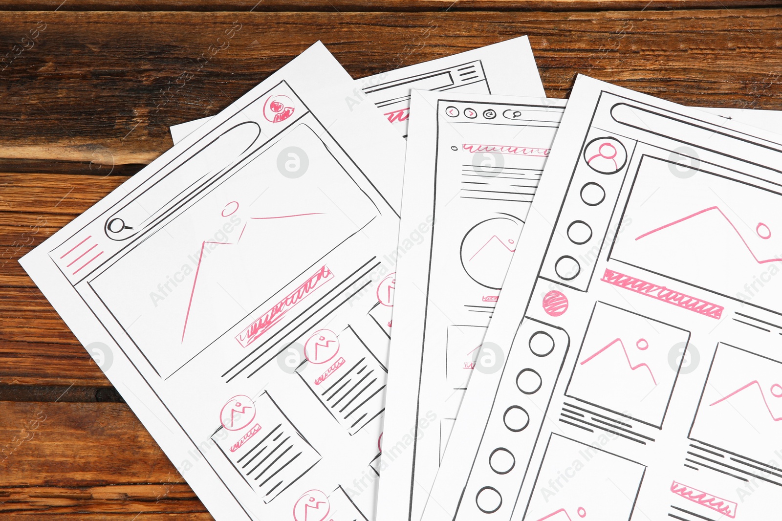 Photo of Developing UI design. Sketches of website wireframes on wooden table, top view