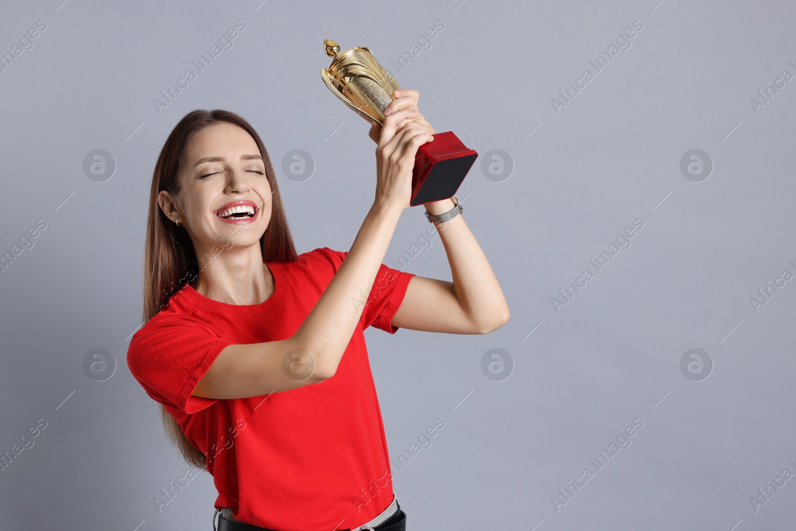 Photo of Happy winner with gold trophy cup on gray background