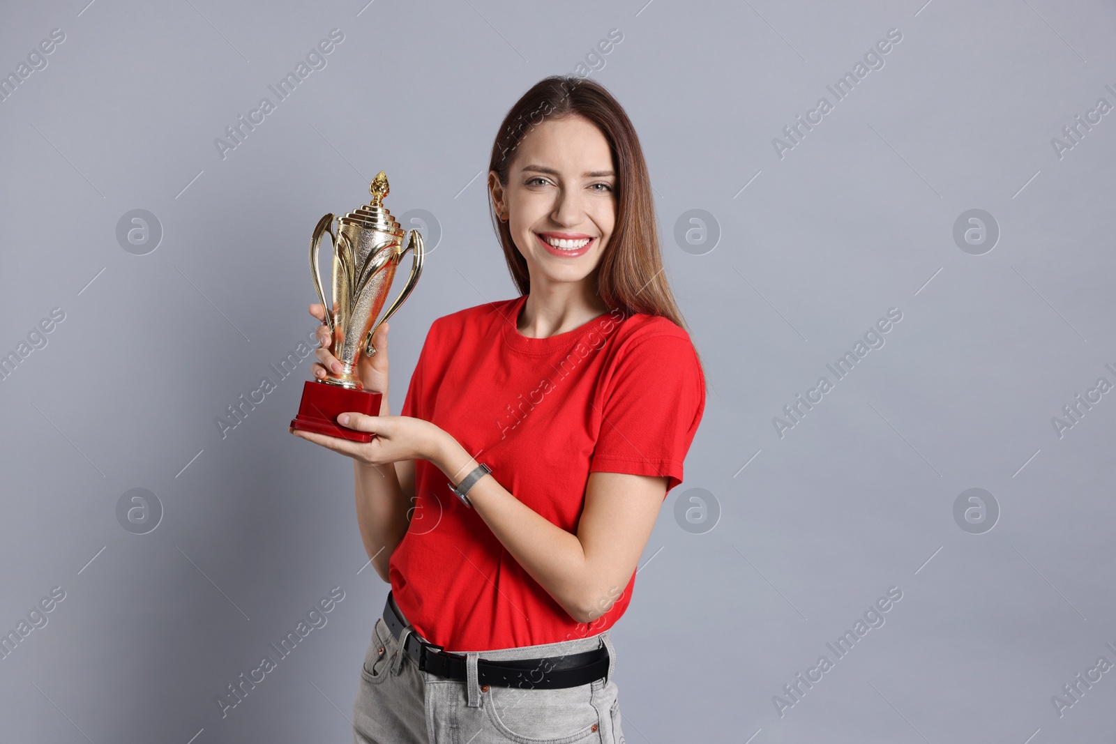 Photo of Happy winner with gold trophy cup on gray background