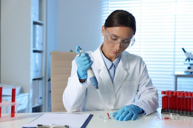 Photo of Laboratory testing. Doctor dripping blood sample into Petri dish at table indoors