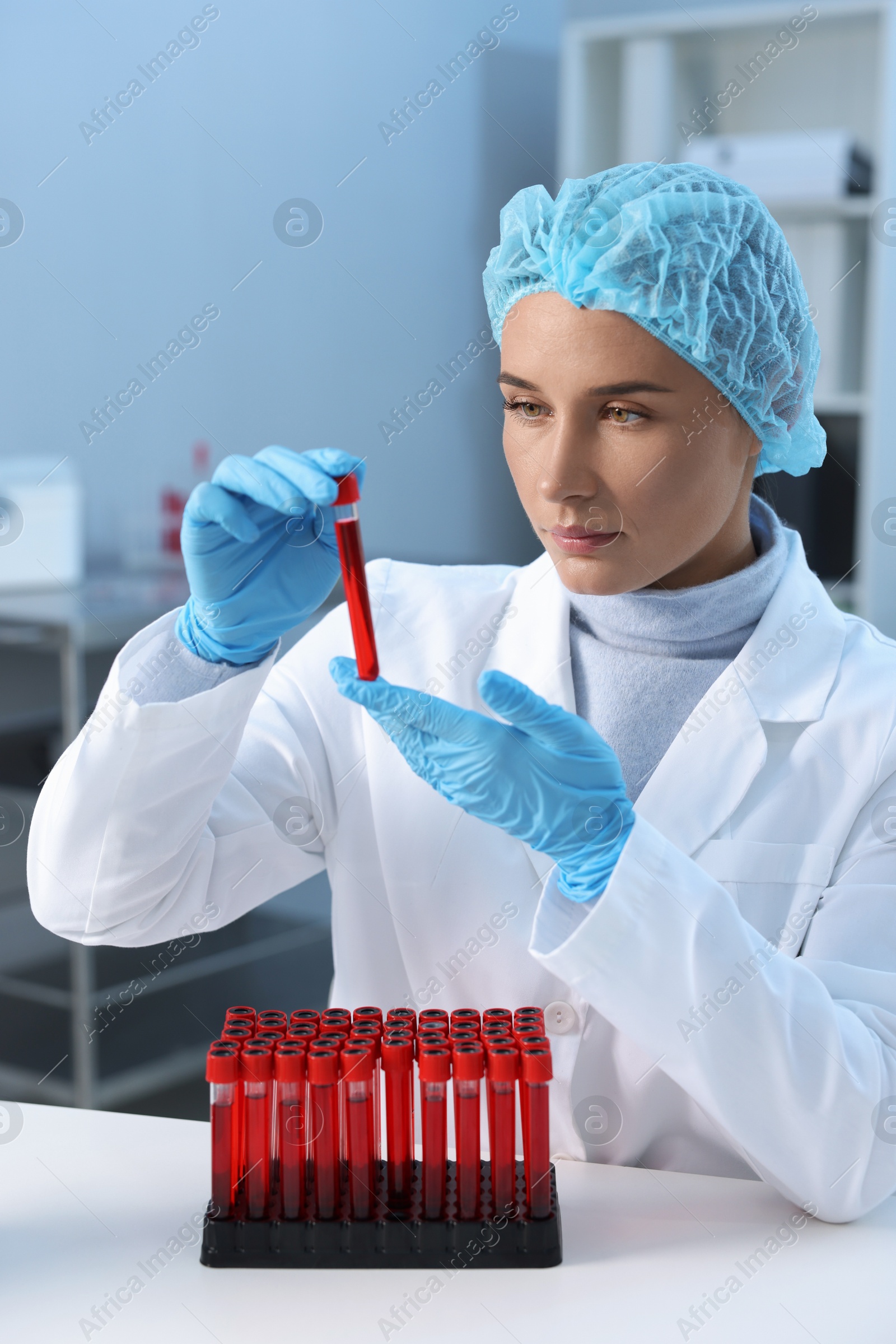 Photo of Laboratory testing. Doctor holding test tube with blood sample at table indoors