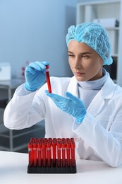 Photo of Laboratory testing. Doctor holding test tube with blood sample at table indoors