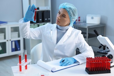 Photo of Laboratory testing. Doctor holding test tube with blood sample at table indoors