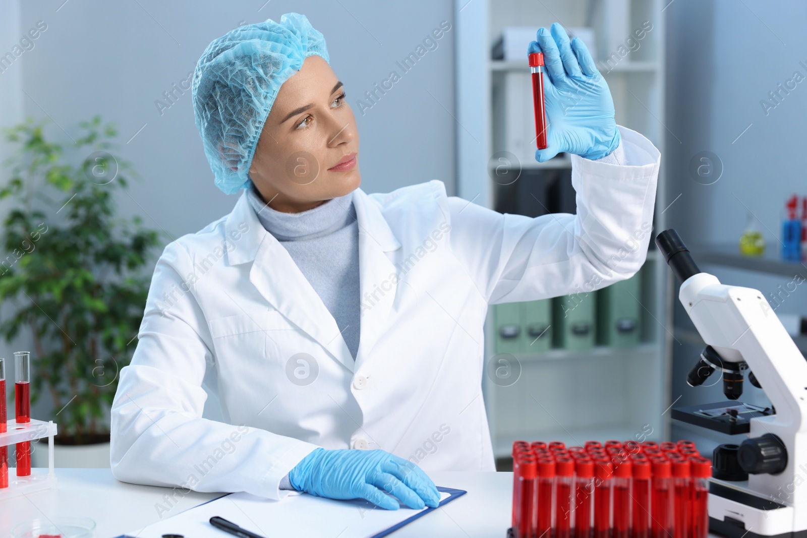 Photo of Laboratory testing. Doctor holding test tube with blood sample at table indoors