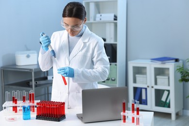 Photo of Laboratory testing. Doctor dripping blood sample into test tube indoors