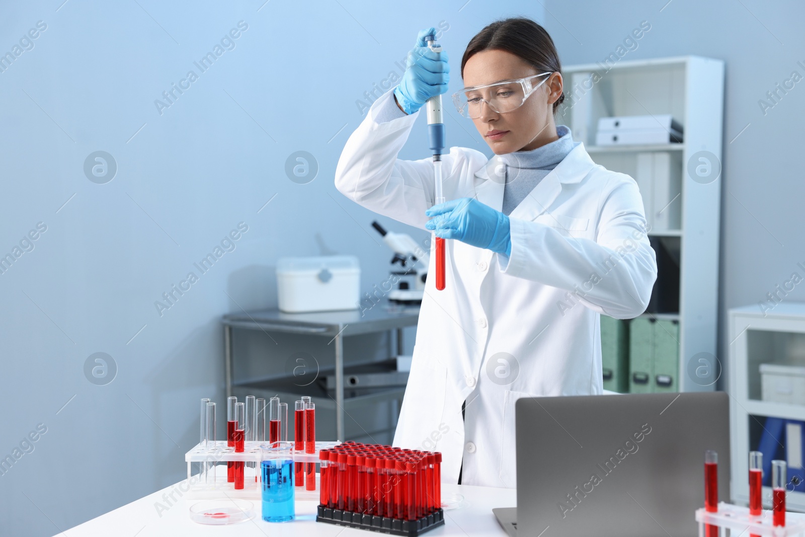 Photo of Laboratory testing. Doctor dripping blood sample into test tube indoors