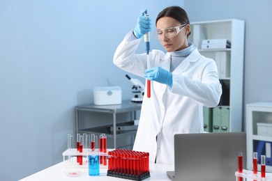 Laboratory testing. Doctor dripping blood sample into test tube indoors