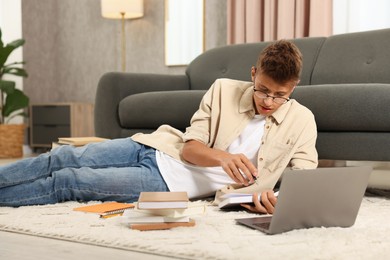 Student in glasses studying on floor at home