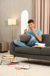 Student studying with laptop on sofa at home