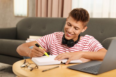 Photo of Student with headphones studying at table indoors