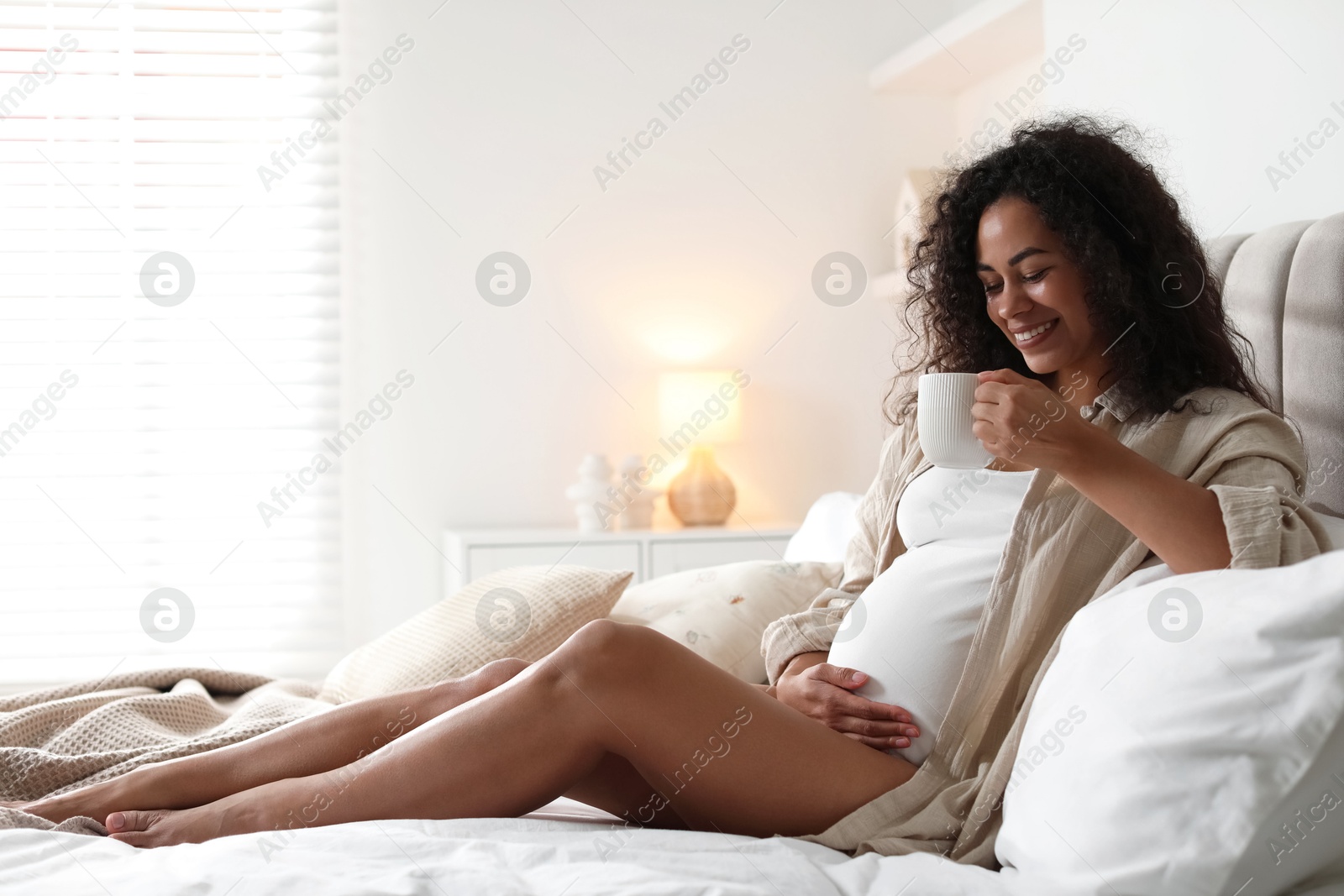 Photo of Portrait of beautiful pregnant with cup of drink on bed at home