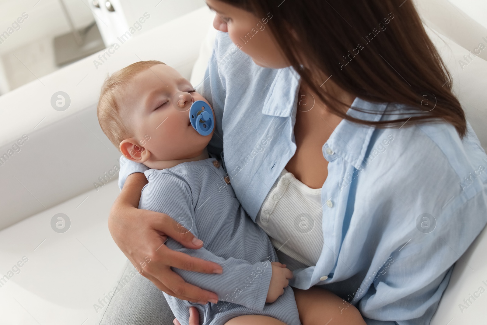 Photo of Mother with her sleeping baby on sofa indoors, closeup