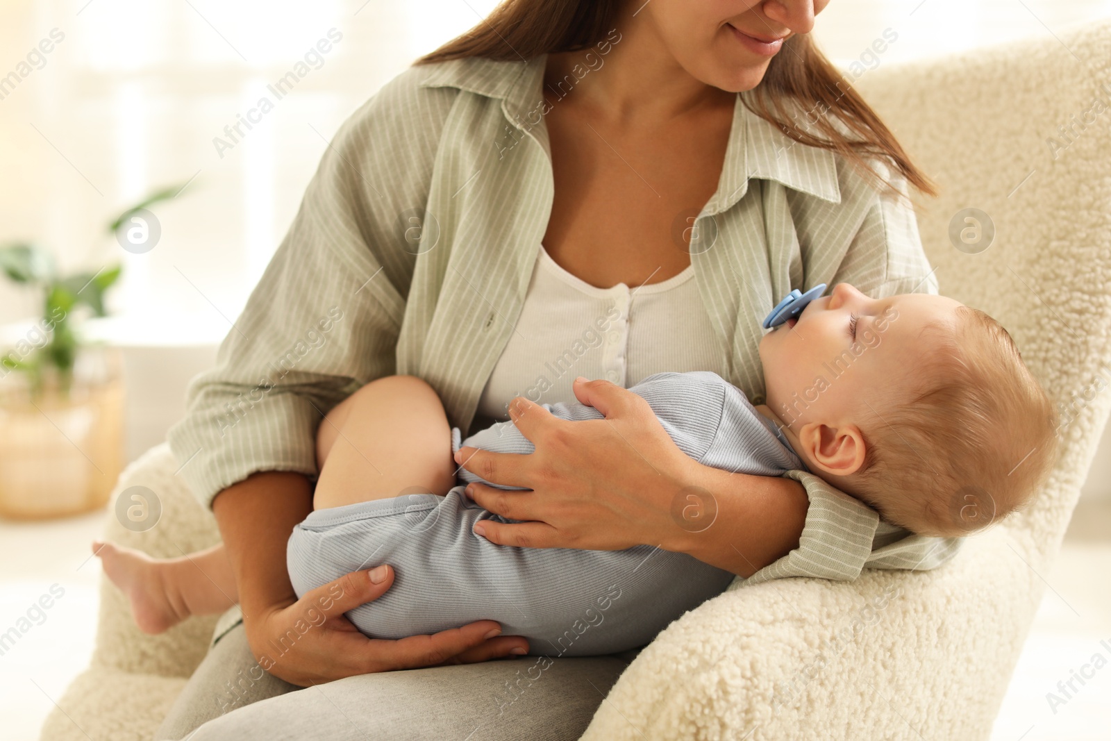 Photo of Mother with her sleeping baby in armchair at home, closeup