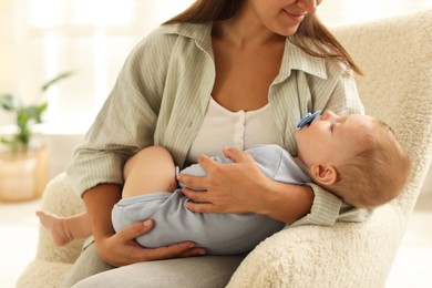 Mother with her sleeping baby in armchair at home, closeup