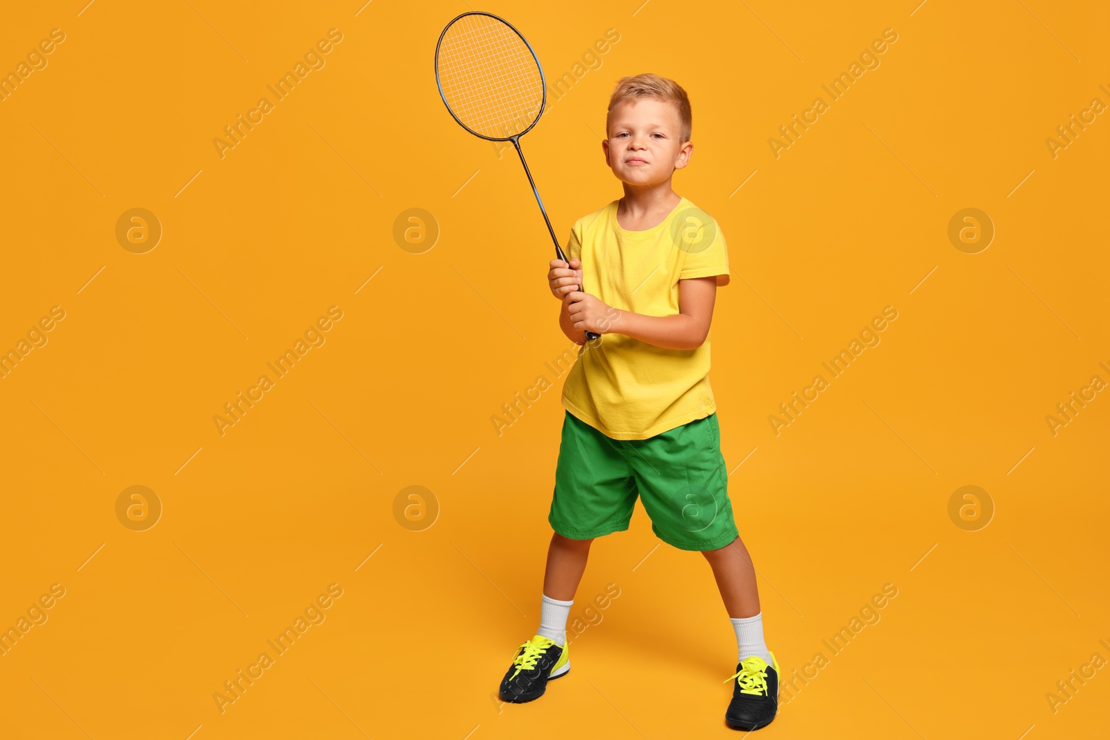 Photo of Little boy with badminton racket on orange background