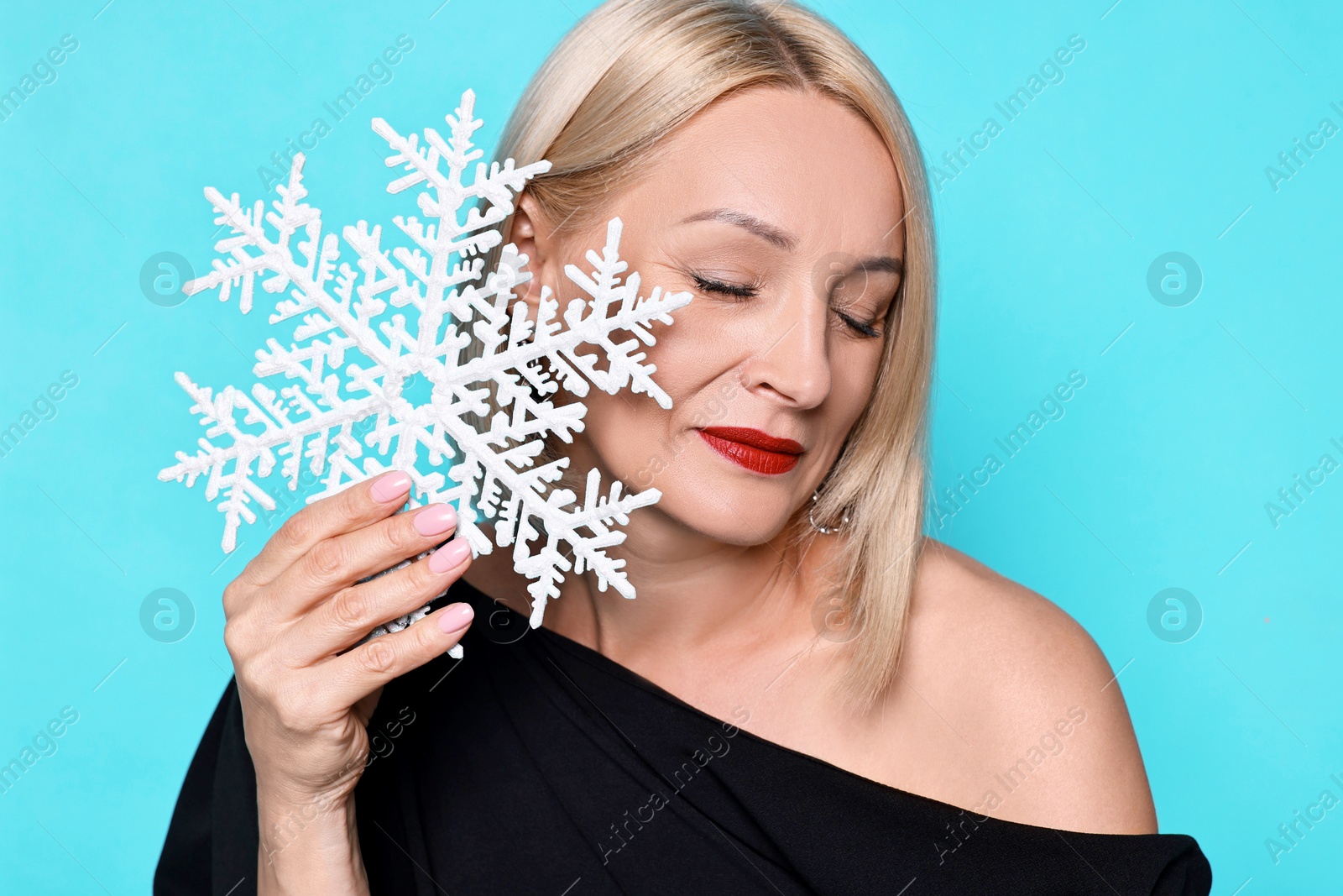 Photo of Woman with decorative snowflake on light blue background. Christmas celebration