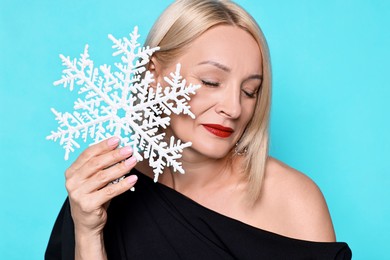 Photo of Woman with decorative snowflake on light blue background. Christmas celebration