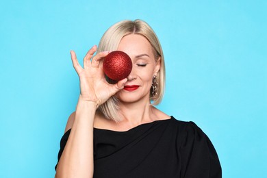 Photo of Woman with Christmas bauble on light blue background