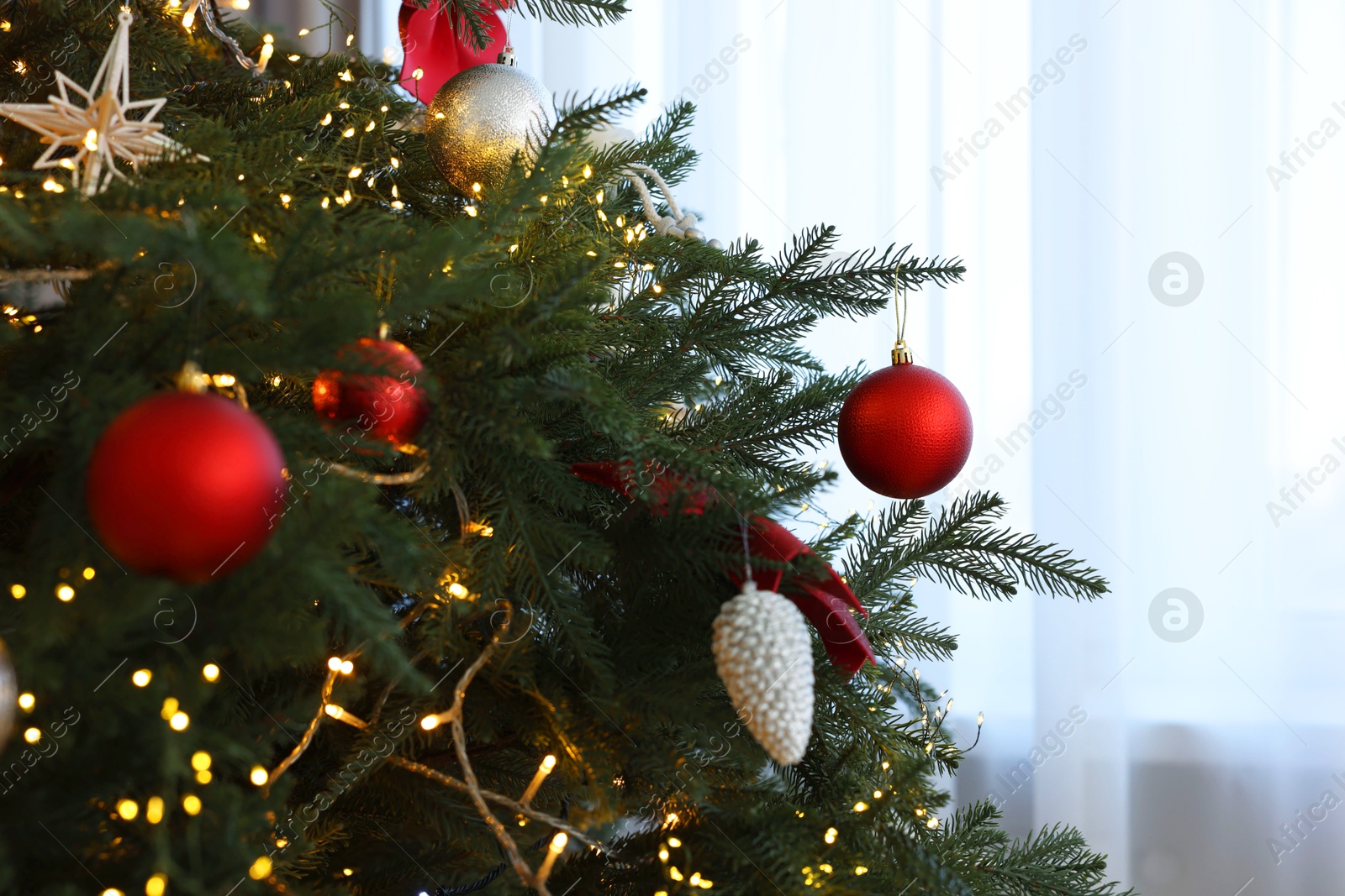 Photo of Christmas tree decorated with beautiful ornaments and lights indoors, closeup