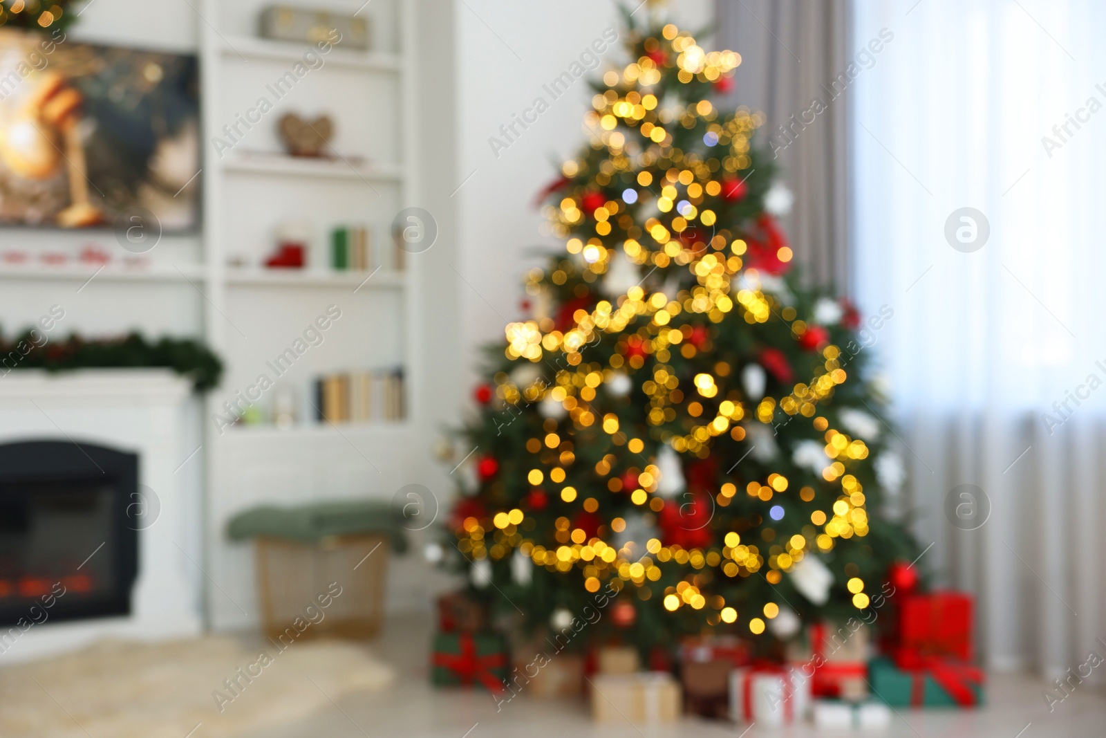 Photo of Blurred view of beautifully decorated Christmas tree near fireplace in room. Festive interior design