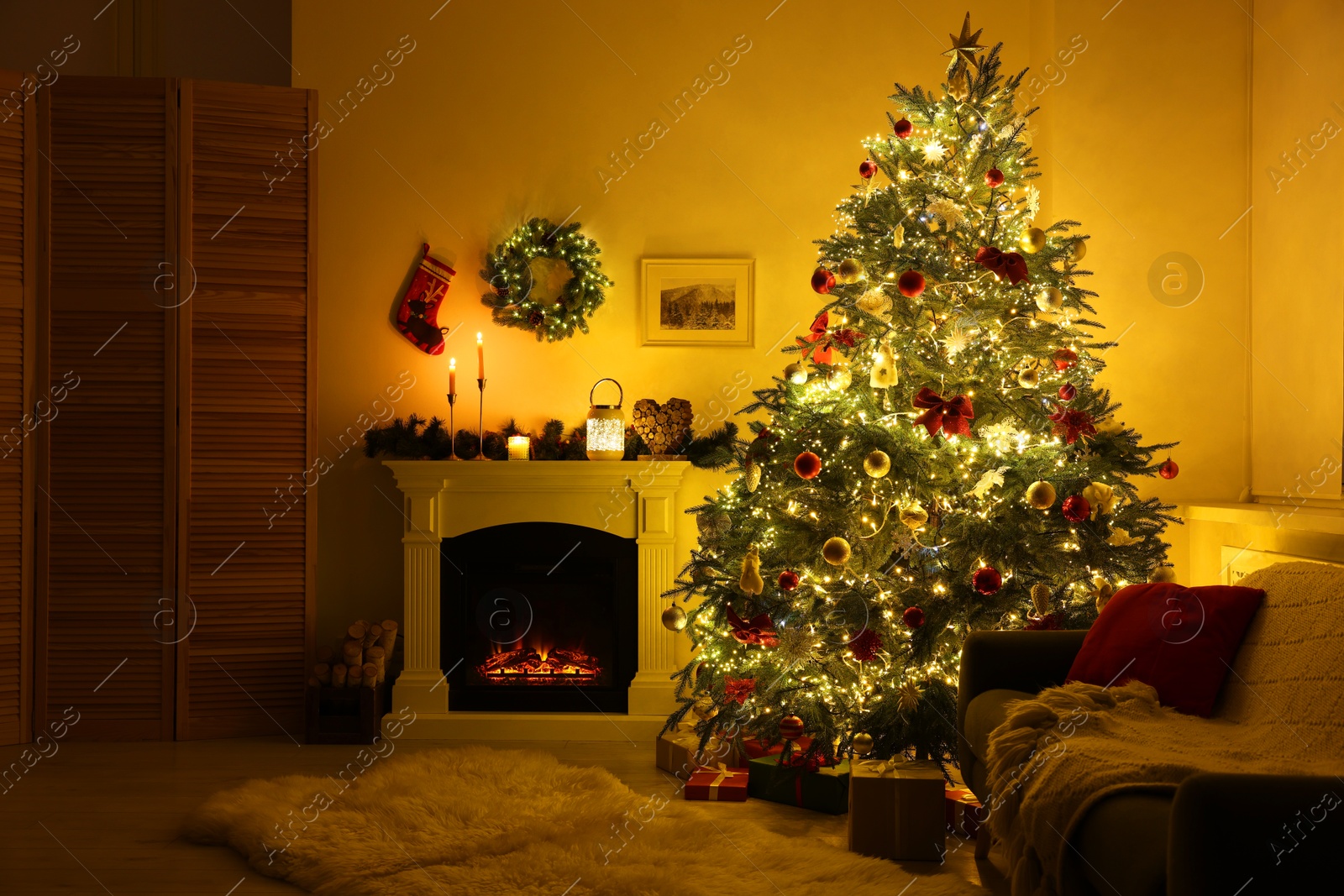 Photo of Decorated Christmas tree near fireplace in room. Festive interior design